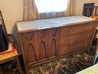Front and left side view of medium brown wood buffet table with decorative doily on top
