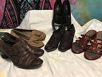 Five pairs of women's shoes arranged on white background showing variety of colors and styles.