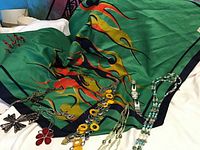 Lot with green Pierre Saint Martin scarf featuring colorful flame abstract design, Swatch watch, and multiple necklaces including cross pendant, red flower pendant, and beaded necklace.