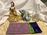 Photo showing all four items including Royal Doulton Sarah figurine, Dansk bunny, Dale Farms milk bottle, and Murano glass dish on cloth background.