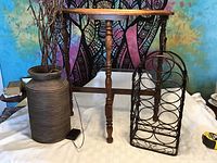 Overall view showing the half moon table with one visible turned leg, decorative jug with dried branches inside, and black metal wire wine rack.