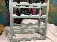 Front view of wooden white painted wine rack showing four shelves with bottle holders