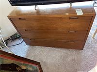 Full front view of the solid wood dresser showing three drawers and wood grain with visible scratches on top and drawer fronts.