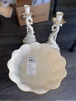 Front view of Lenox scalloped bowl with 24kt gold trimmed edge alongside two candleholders with detailed scroll and leaf design and gold accents.