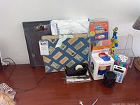 Photo of the lot on desk including tape dispenser, file folders, portfolio, Angry Mama cleaners, USB cleaner, calculator, and container of erasers.