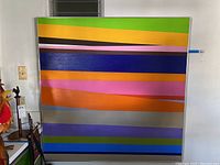 Front view of large square canvas wall art in metal frame with horizontal colorful stripes.