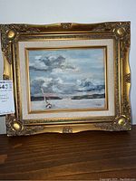 Front view of signed seascape oil painting in a detailed gold frame.