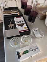 Wine opener box with corkscrew, pocket guide, and wine stopper box; three purple glasses; two cut glass candle holders; crystal ashtray.