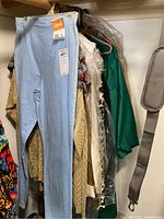 Light blue stretch pants with size Large Petite tag by Faded Glory hanging among other clothing items on hangers.