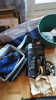 Overview of assorted bags and storage bin on hardwood floor near window