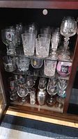 Three shelves filled with assorted glassware, crystal and barware items