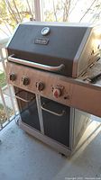 Front and side view of Dyna-Glo gas grill BBQ highlighting controls and temperature gauge on lid.