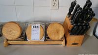 Photo showing three glass canisters with wooden lids and a wooden knife block filled with knives