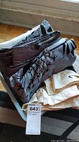Folded black and grey drapes and beige drapes stacked in a container.