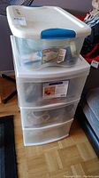 Full view of four plastic storage drawers and a plastic bin on top, containing assorted hardware items.