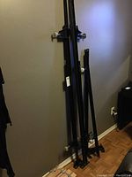 Black metal bed frame rails and support bars with mounting screws and plastic end caps leaning against wall.
