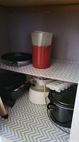 Frying pans, crockpot, steamer baskets, and additional kitchenware on shelves