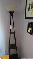 Full view of the 3-tier lamp showing the black metal frame, three shelves, and the frosted glass bowl shade.