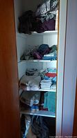 Photo showing linen shelves with folded bedsheets and towels in multiple colors stacked horizontally