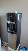 Front view of Primo water cooler showing upper black control section and lower stainless steel section