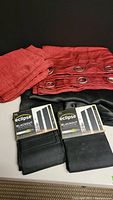Red fabric curtains with metal grommets and two Eclipse brand black blackout curtain liners.