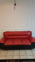 Front view of red and black leather couch showing three seat cushions and backrest.
