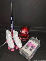 White roller skates with pink wheels, blue Louisville Slugger baseball bat, red Rawlings baseball helmet, and boxing gloves in box