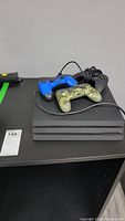 Black PS4 Pro console with three controllers on top