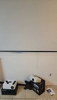 White pull-down screen mounted on wall above baseboard
