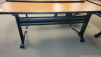 Close-up of the modesty panel and wood laminate top of table, showing front frame and leg structure.