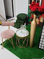 Setup showing the vanity chair, mirrored table, tall gold-toned vase with faux flowers, and two wine glasses on artificial grass
