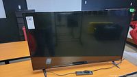 Front view of Vizio flat screen LED TV with stand and remote in front.