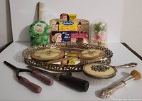 Full lot showing tray, hand mirror, brush, curling irons, makeup brush, hairpins, comb, flower container, and sewing needles in original packaging.