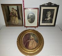 Photo of the four framed Victorian women portraits arranged on a white surface with measuring tape for scale.