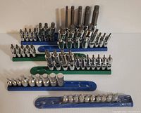 Full view of six rails of GearWrench bit sockets. Green rails with flexing Torx/eTorx bits and blue rails with metric bits, showing a variety of bit sizes and socket styles.