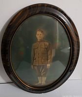 Front view of vintage soldier portrait in oval wooden frame with convex glass.