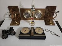 Full lot of 7 items including brass armillary bookends, Galileo thermometer, barometers, binoculars, folding glasses.