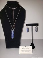Full view of the sodalite necklace on display bust; matching sodalite earrings on stand; small card describing sodalite stone properties.
