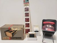 Photo showing the slide viewer, original box, and multiple sets of slides including Pearl Harbor, Clearwater Florida, and Virginia vacation scenes.