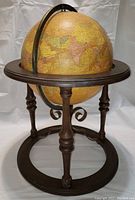 Front view of vintage globe on wooden stand showing map of Middle East, Africa and Europe with metal meridian and compass base.