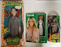 Front view of all three dolls in their original boxes: Pee-Wee Herman talking doll, Farrah Fawcett doll, and Dr. Evil doll with Austin Powers branding.