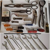 Photo showing assorted hand tools including scissors, screwdrivers, wrenches, pliers, and a battery tester laid out on a white surface.