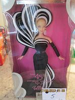 Front view of the unopened 2003 Bob Mackie Barbie doll in clear collector box with pink background and black and white gown visible.