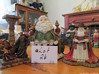 Photo showing three items: Fritz and Floyd Santa, two candle holders, all on wooden table with surrounding furniture visible.