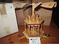 Overall view of the wooden pyramid carousel with upper and lower tiers, propeller blades on top, and candle holders on sides.