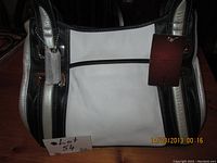Front view of the handbag showing black and white leather color blocking with attached Tignanello brand tag and handles