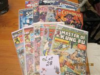 A set of 12 vintage comic books including Master of Kung Fu, Superman, and Catwoman with visible cover art and titles, mostly bagged and boarded.