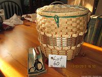 Wicker sewing basket with handle and packaging including pinking shears on a wooden table