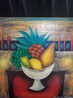Full view of the canvas painting showing a white pedestal fruit bowl containing a pineapple, green grapes, lemon, and pear with textured colorful background.