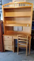 Full view of the child's desk and hutch with attached shelves, three drawers on left, missing two knobs, and matching wooden chair